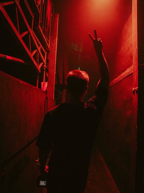 A guest raising a hand beneath warm red light at UNITED.